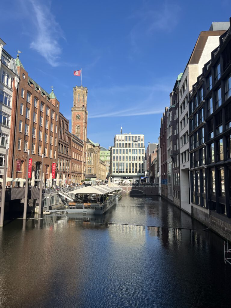 Alsterfleet mit Backsteinhäusern, Barkasse und dem Rathausturm im Hintergrund